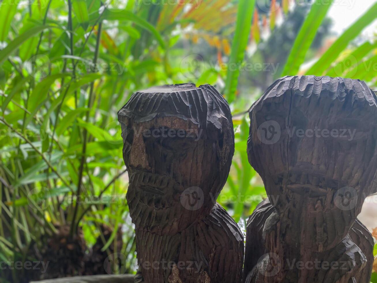 Two wooden statues of people sitting in a pot photo