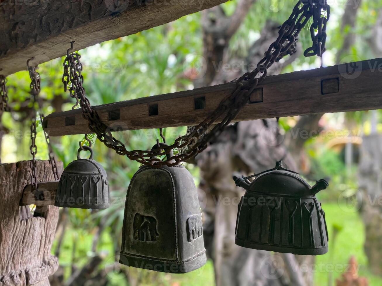 Bells hanging from a wooden structure in a garden photo