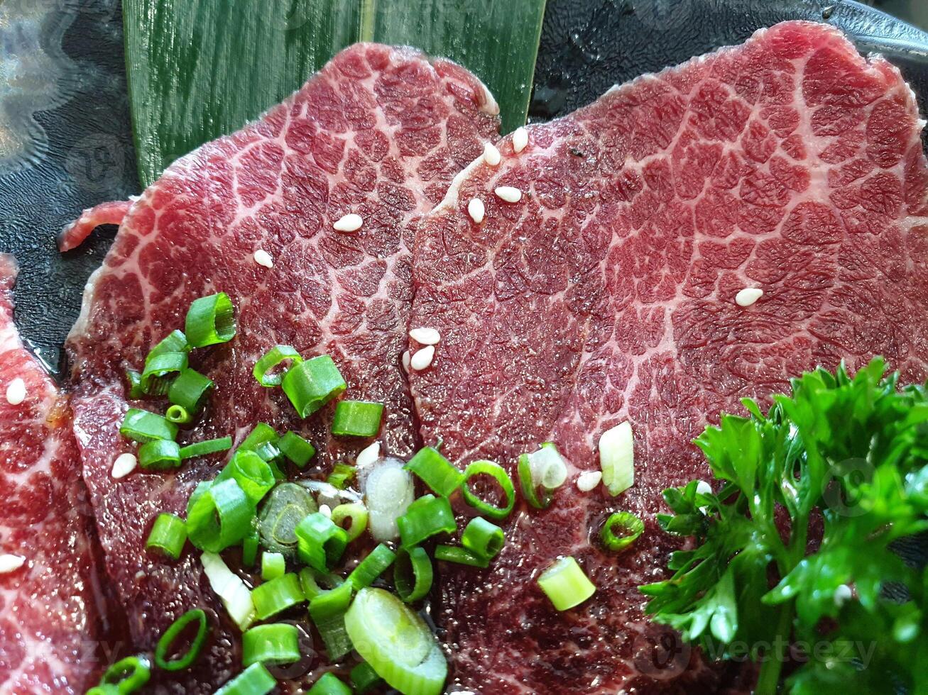 A plate of meat with green onions and parsley photo