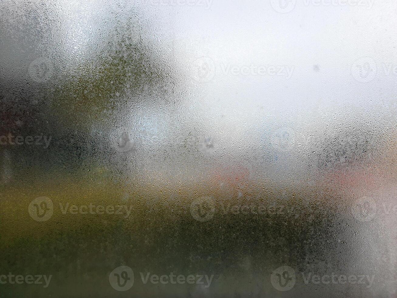 A blurry view of a wet window with a street in the background photo