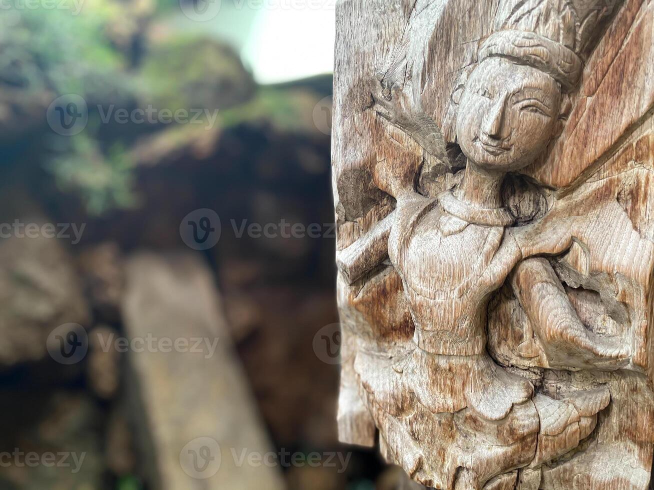 A wooden carving of a woman holding a flower photo