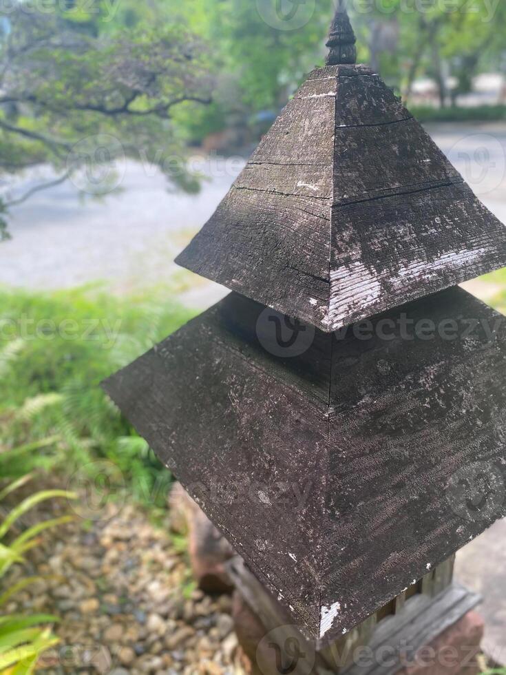 A wooden lantern sitting on top of a stone photo