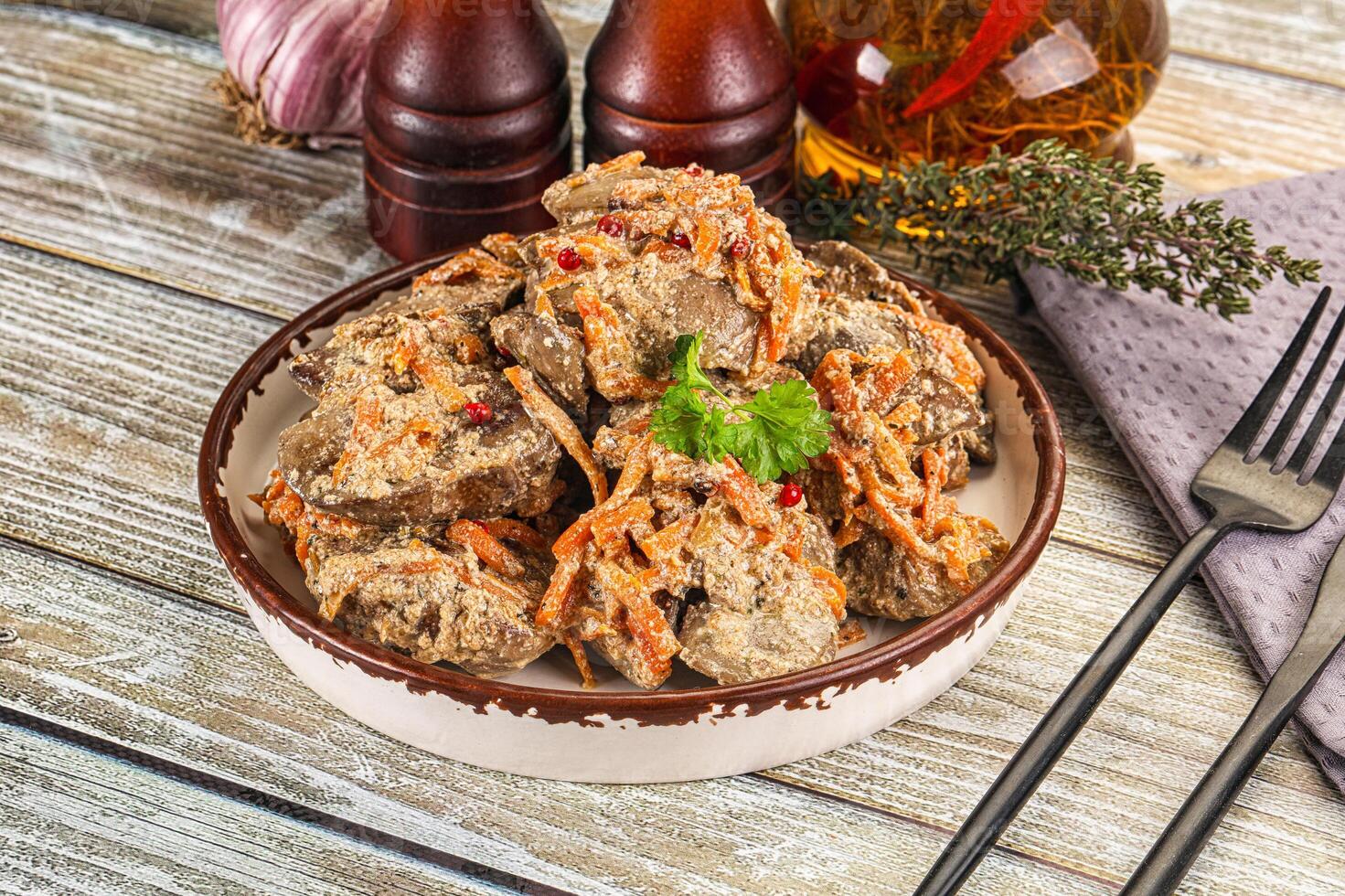 A bowl of meat with sauce and spices on a wooden table photo