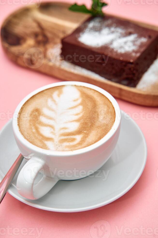 Latte art and chocolate cake on pink table photo