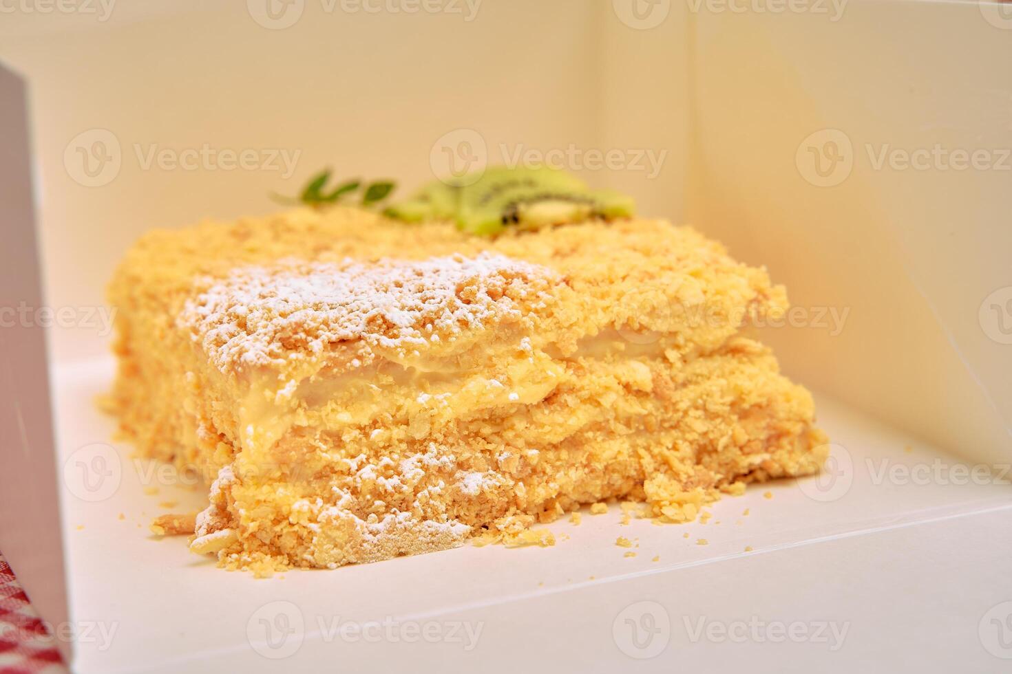 Delicious creamy layered pastry with kiwi garnish in white box photo