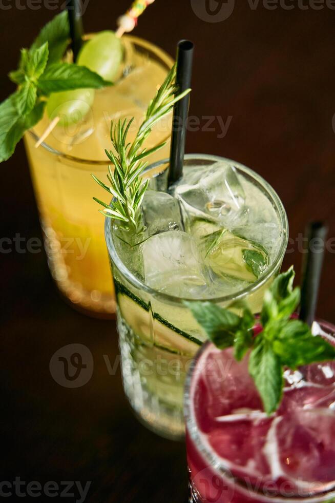 Colorful refreshing cocktails with mint and rosemary garnishes on table photo