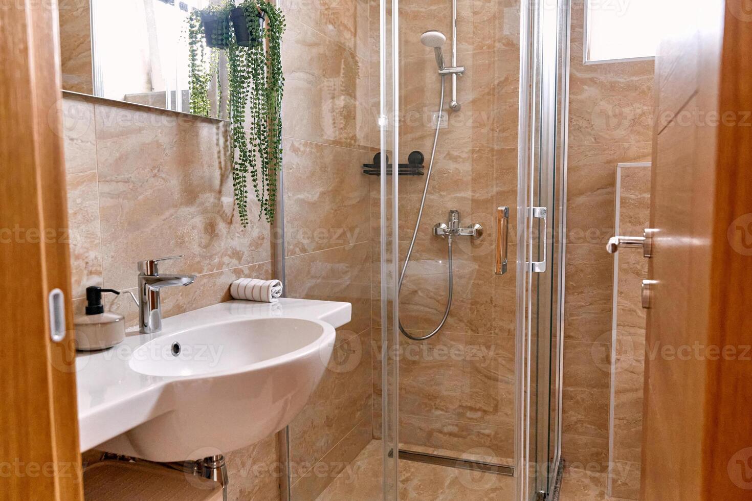 Modern natural bathroom design with beige tiles and glass shower enclosure photo