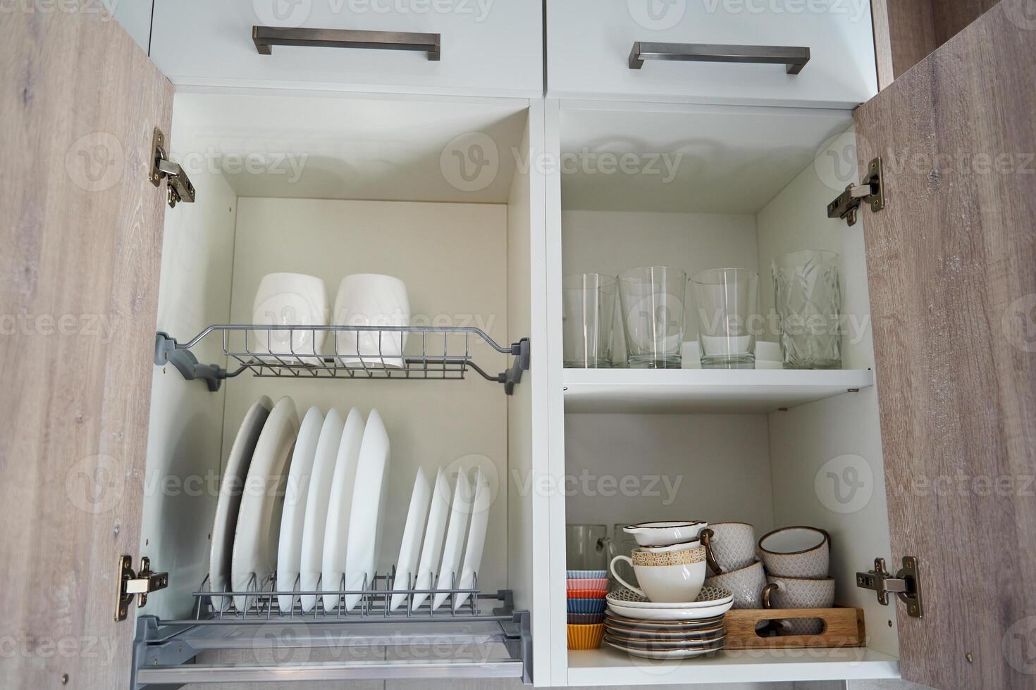 Organized kitchen cabinet with plates, bowls, and glassware in neat storage arrangement photo