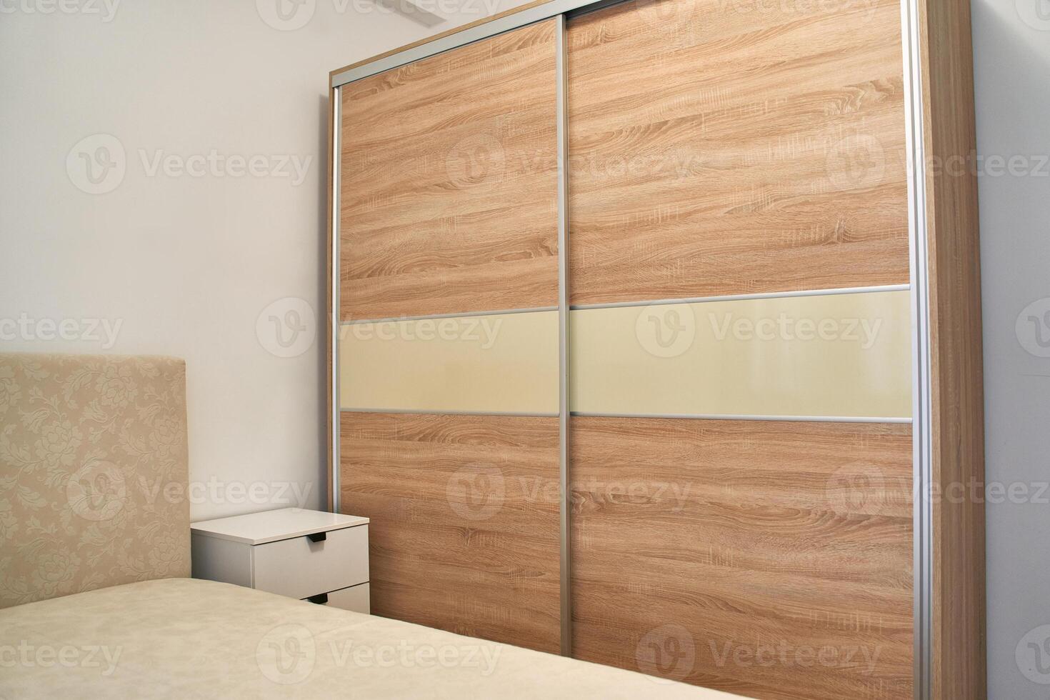 Wooden sliding wardrobe and beige bedroom furniture in minimalist design photo