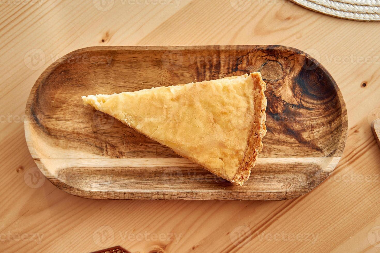 Golden apple pie slice on rustic wooden platter in cozy kitchen setting photo