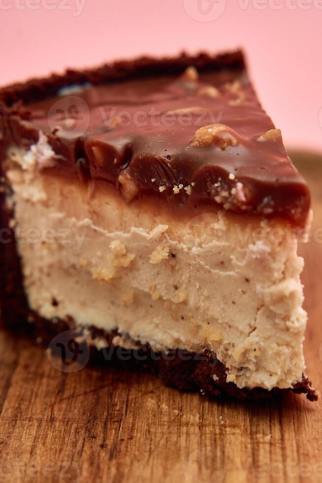 Delicious chocolate peanut butter cheesecake slice with rich ganache on wooden board photo
