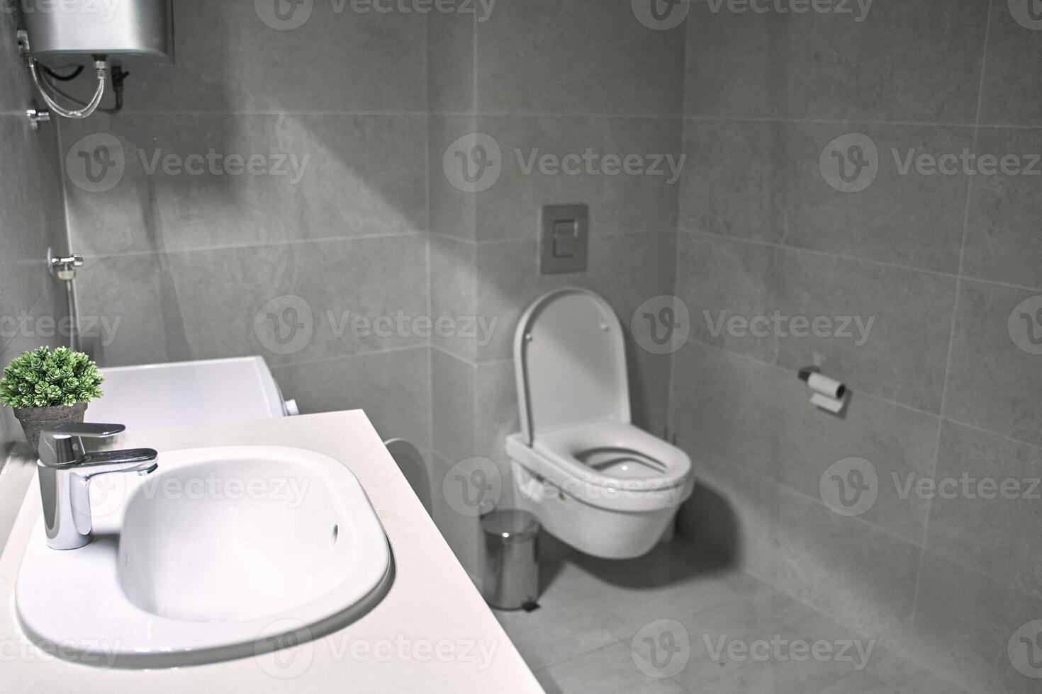 Modern bathroom with wall-mounted toilet and sink featuring minimalistic design photo