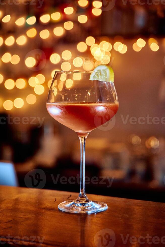 Elegant cocktail glass with lemon garnish in warm ambient lighting photo