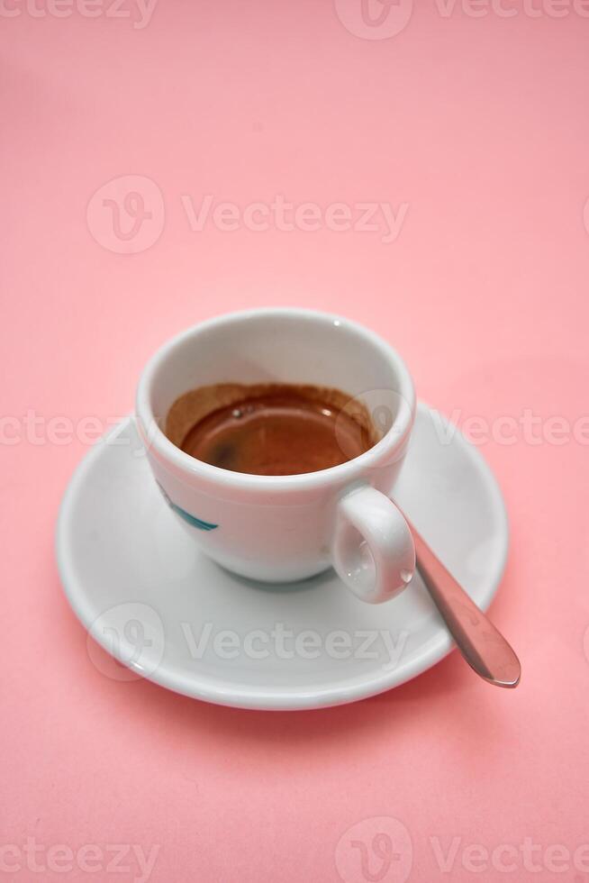 Minimalist white espresso cup on soft pink background with stainless steel spoon photo