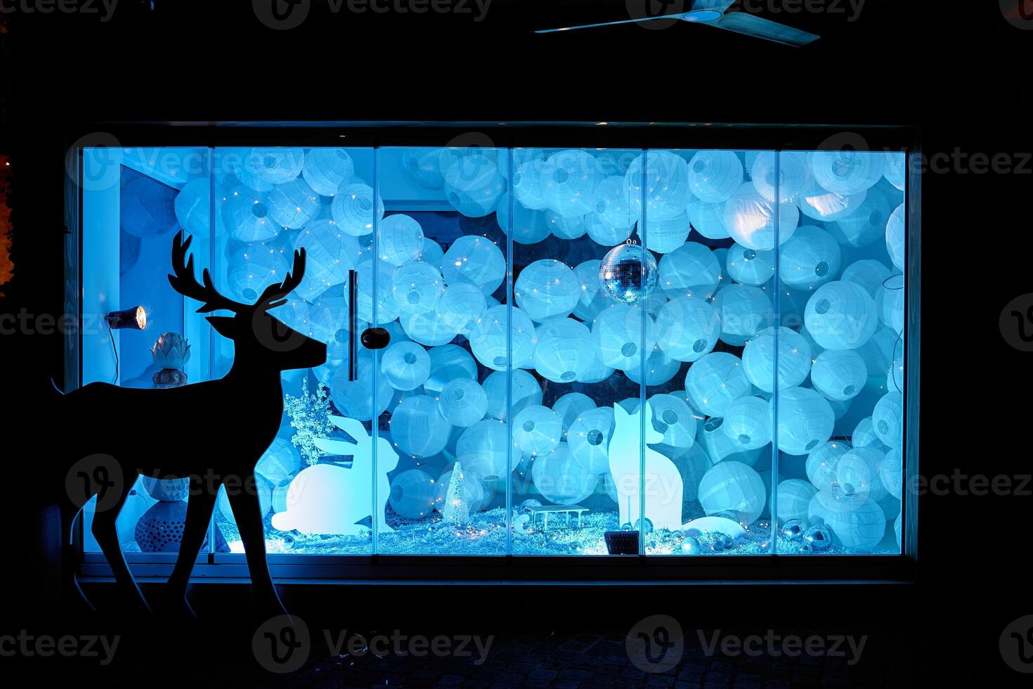Enchanted winter display illuminated deer silhouette with blue lit orbs in window photo