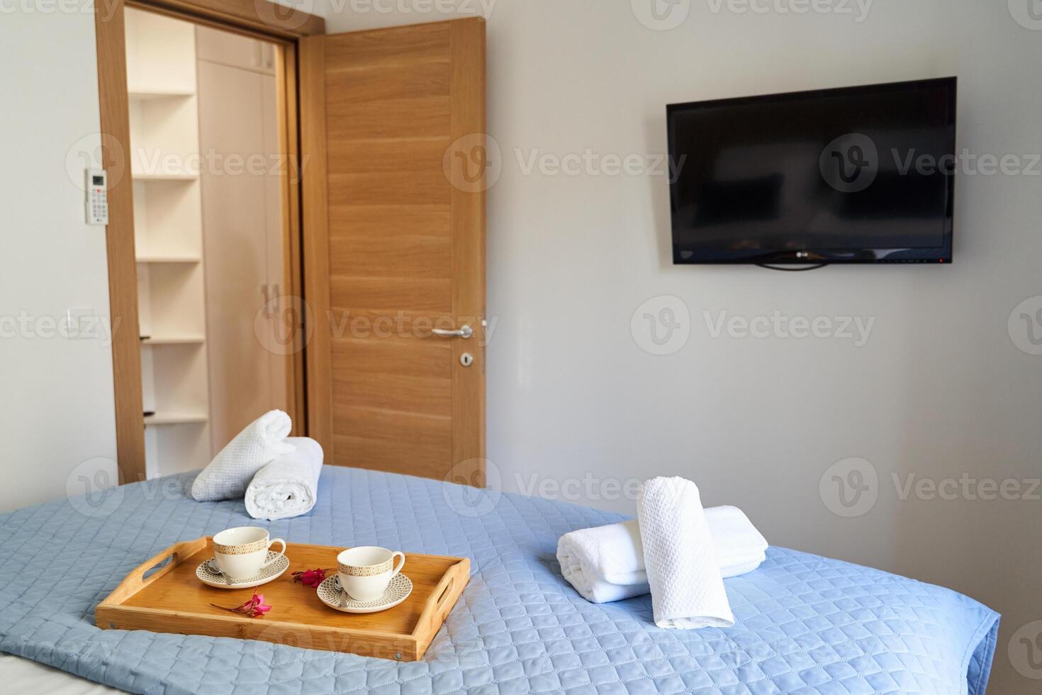 Cozy bedroom with tv and wooden door featuring a neatly made bed and refreshment tray photo