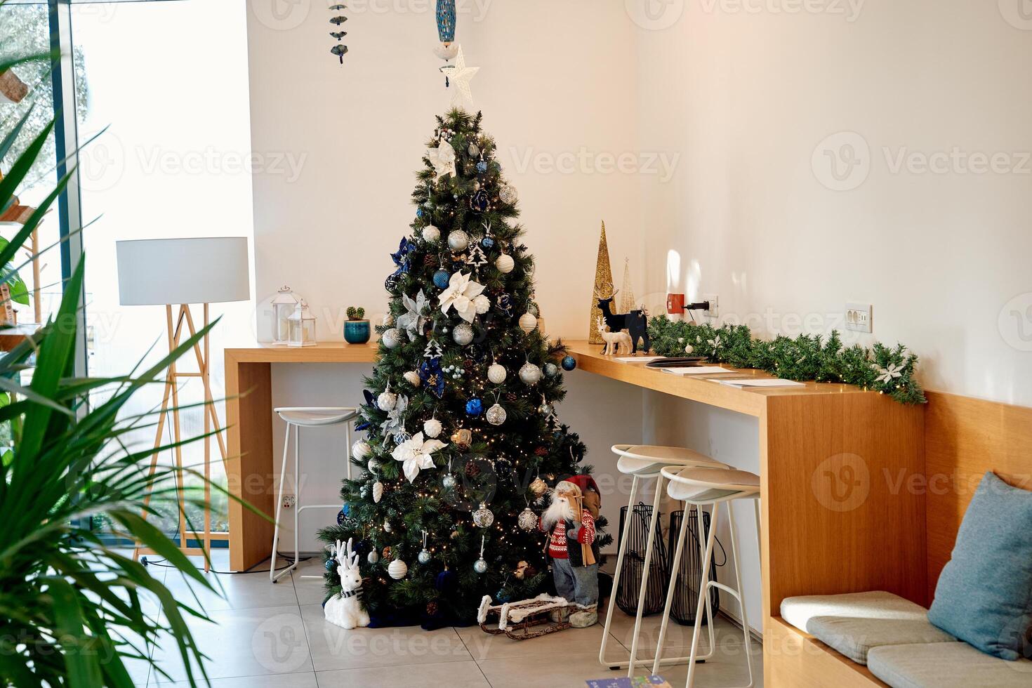 Elegant christmas tree in minimalist cafe decorated with ornaments and gifts photo