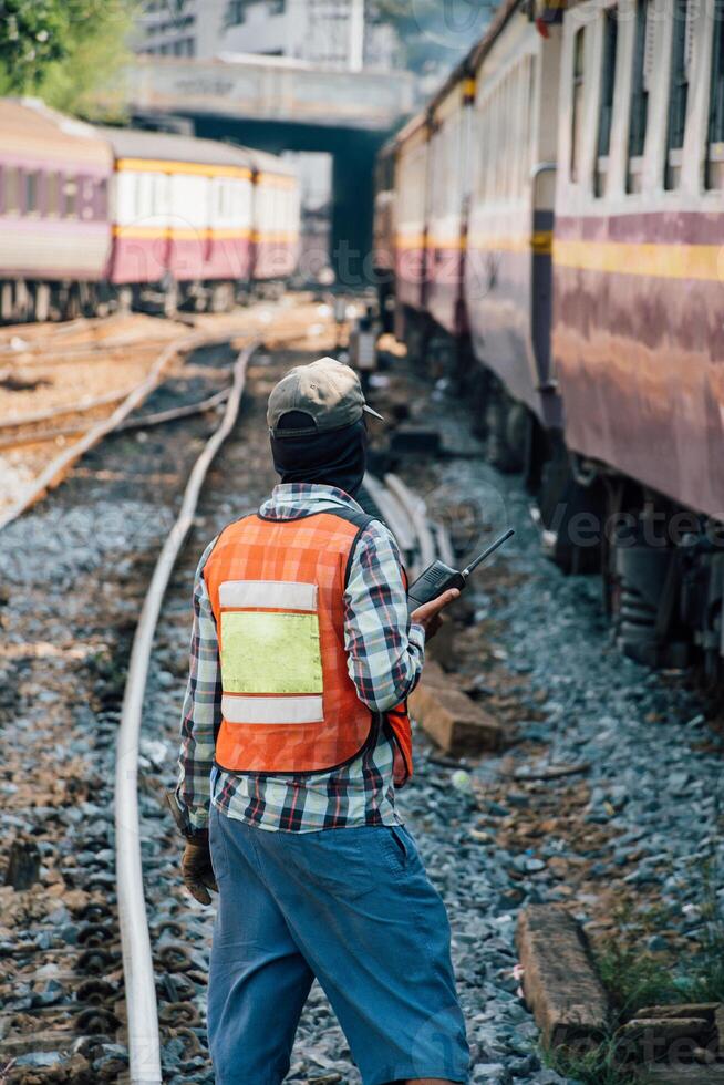 A man standing on the tracks next to a train photo