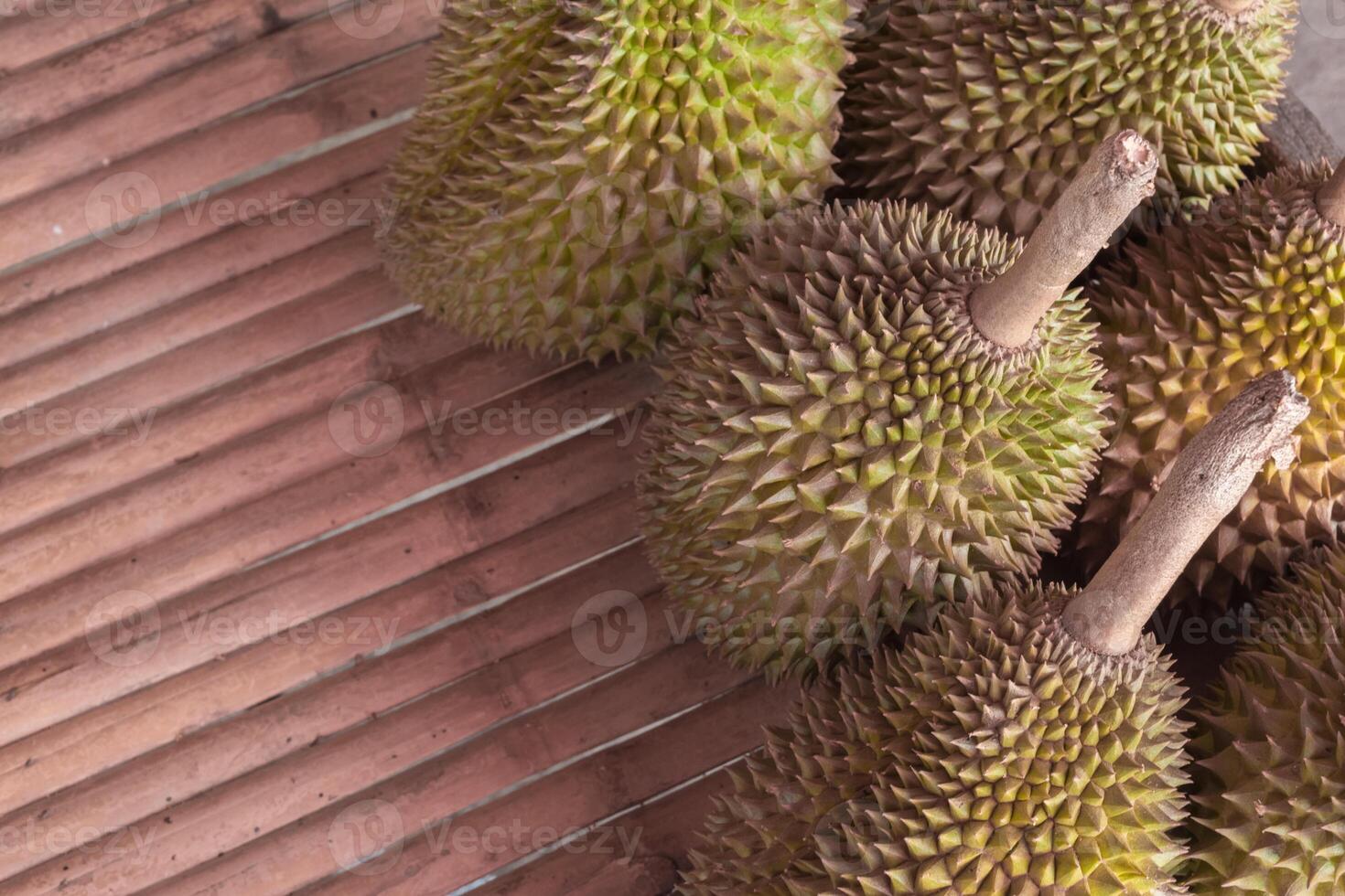A bunch of durian fruit sitting on a wooden table photo