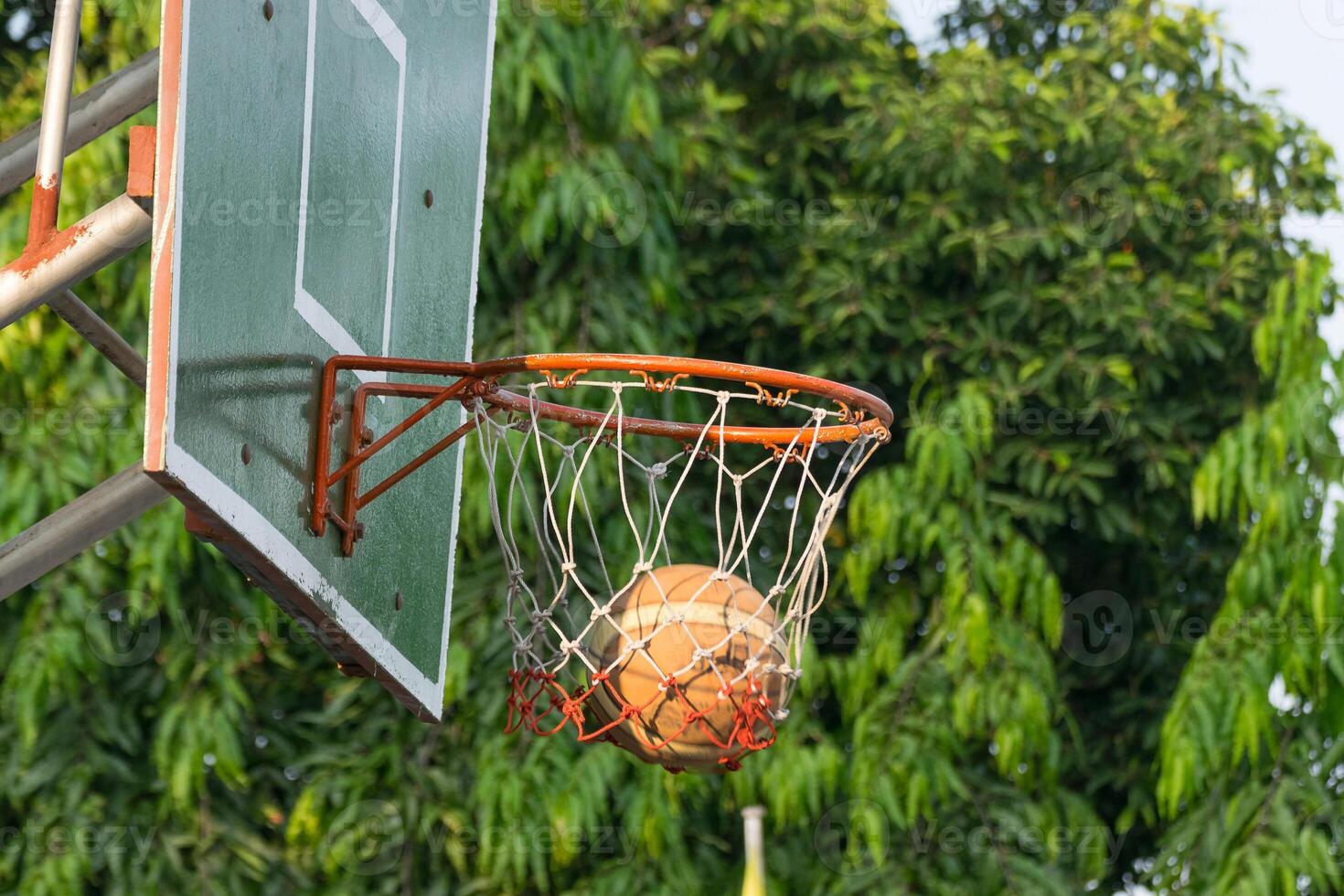 A basketball is hanging from the rim of a basketball hoop photo