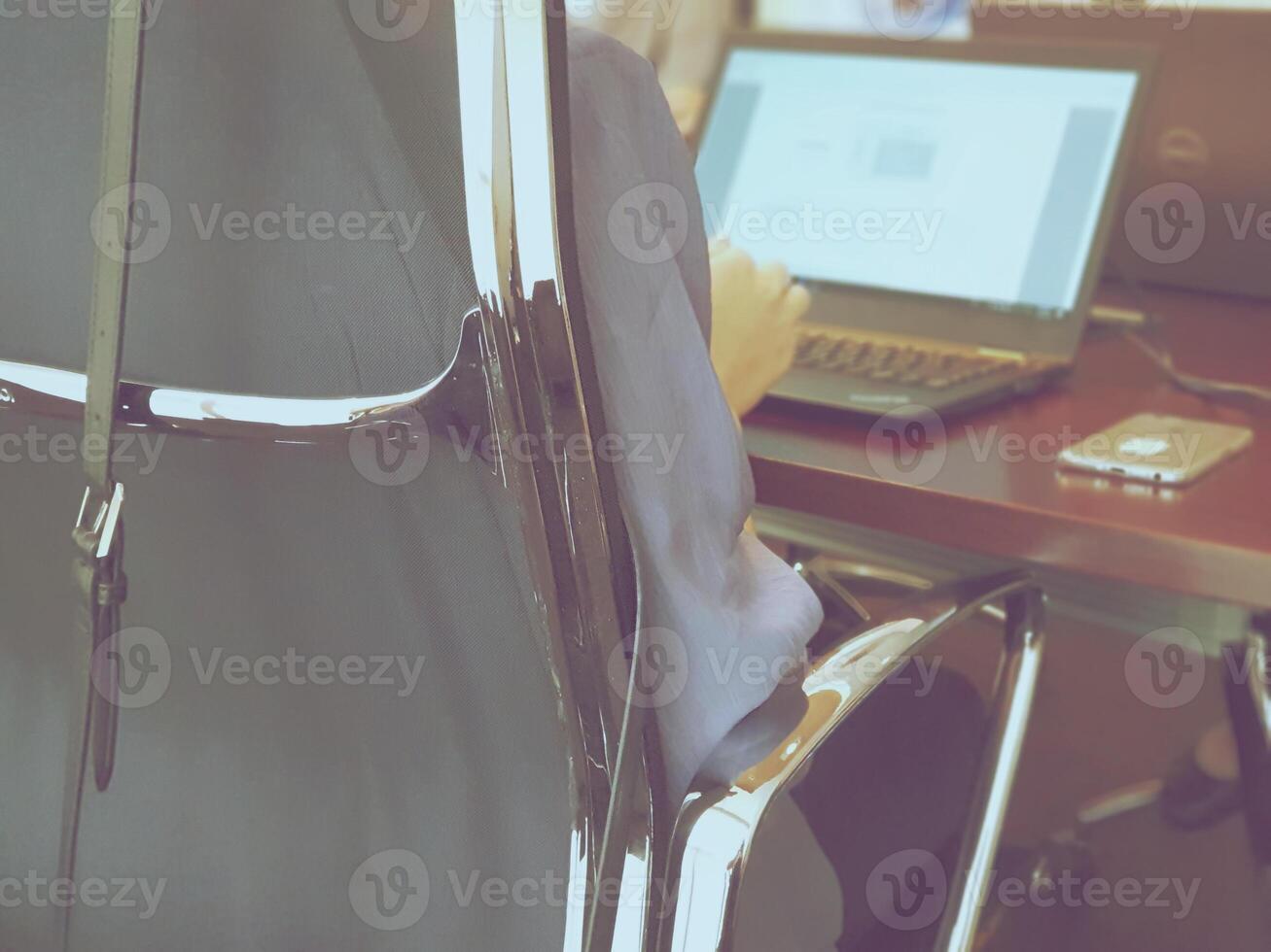 A person sitting in a chair with a laptop computer photo