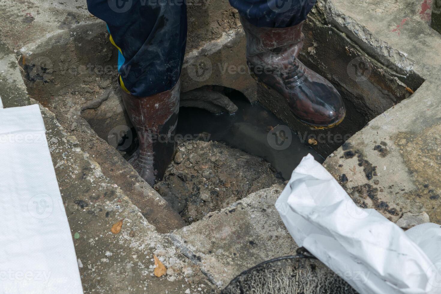 A man standing in a hole with a bag of trash photo
