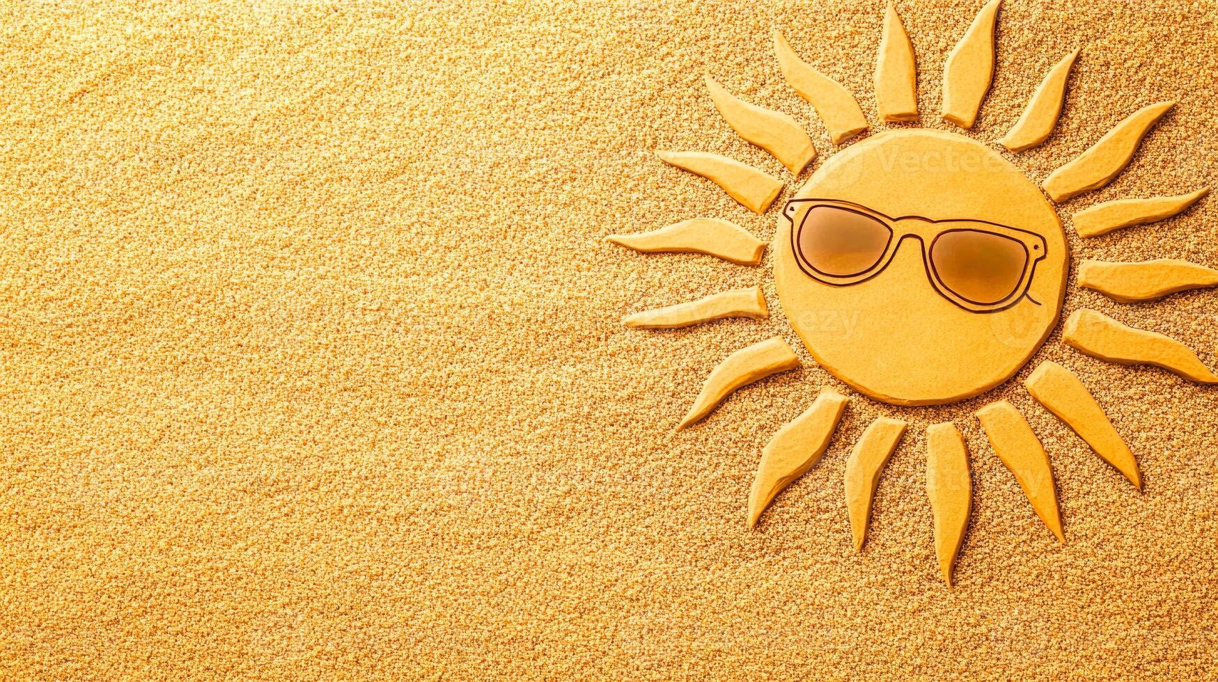 Sunshine with sunglasses on warm sand. A cheerful sun wearing sunglasses rests on a smooth bed of golden sand, evoking a warm beach atmosphere. photo