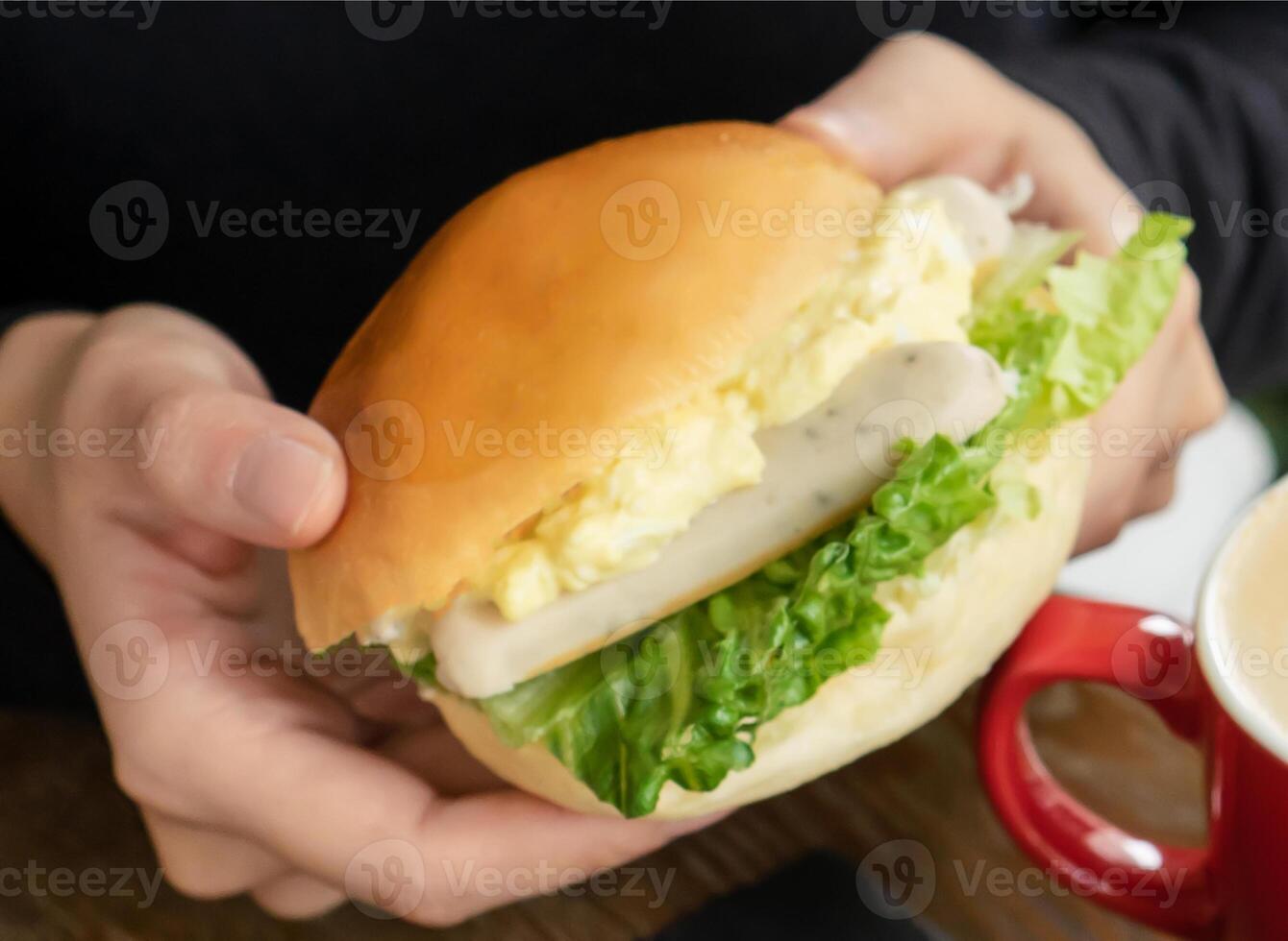 Holding a Delicious Sausage and Egg Salad Brioche Bun with Fresh Lettuce closeup view of breakfast meal photo
