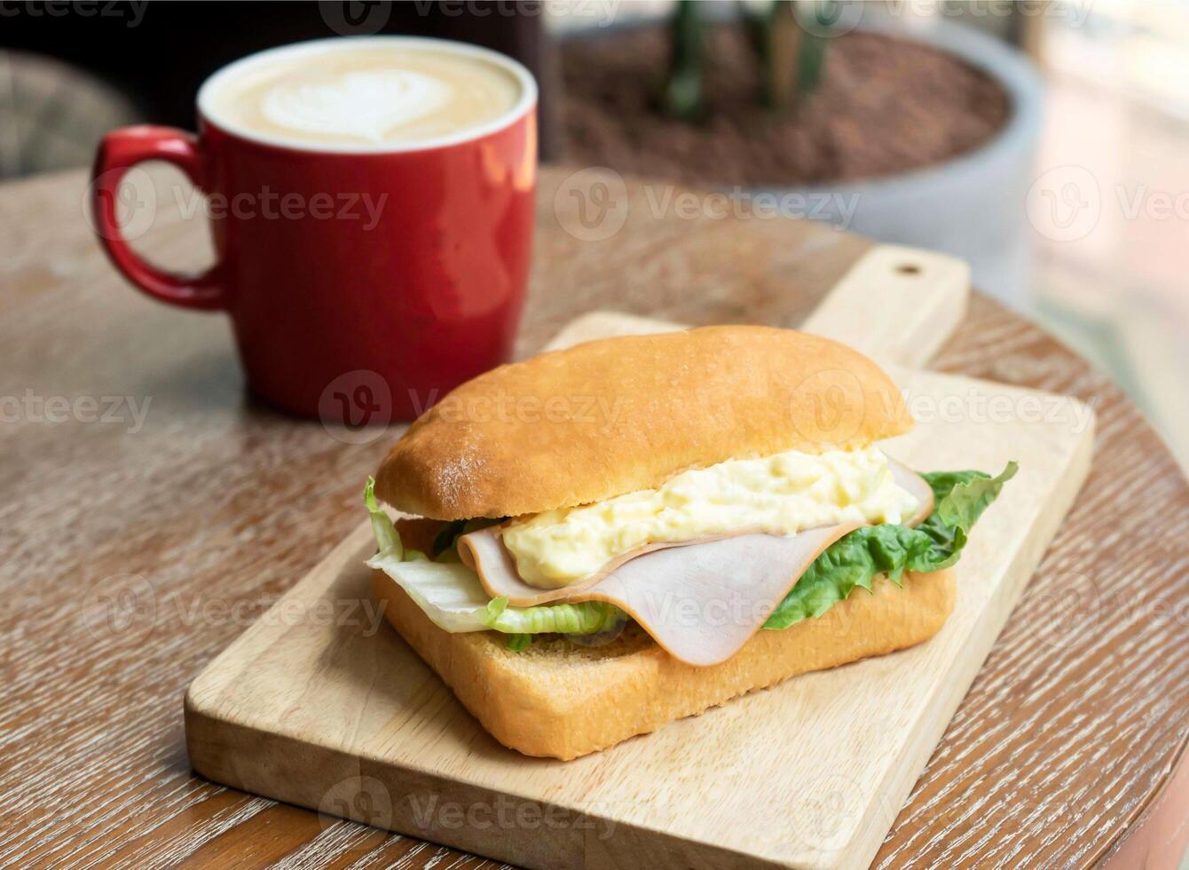 Savory Smoked Ham, Egg Salad, Lettuce Focaccia on wooden board with cup of Coffee side view of breakfast photo