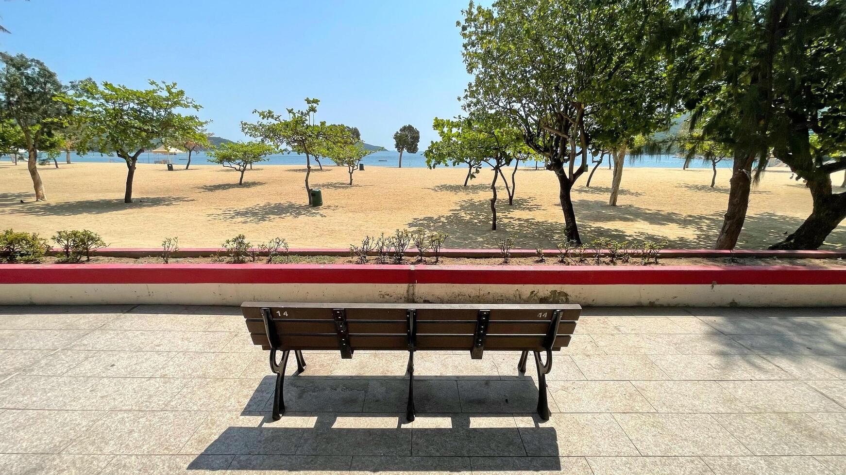 Garden beach, sands, trees, water, garden wooden bench in Hong Kong Repulse Bay photo