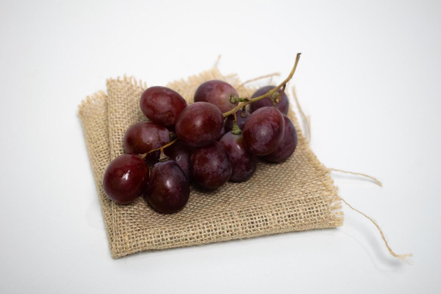 Fresh red grapes placed on a rustic piece of burlap fabric, simple and natural. photo