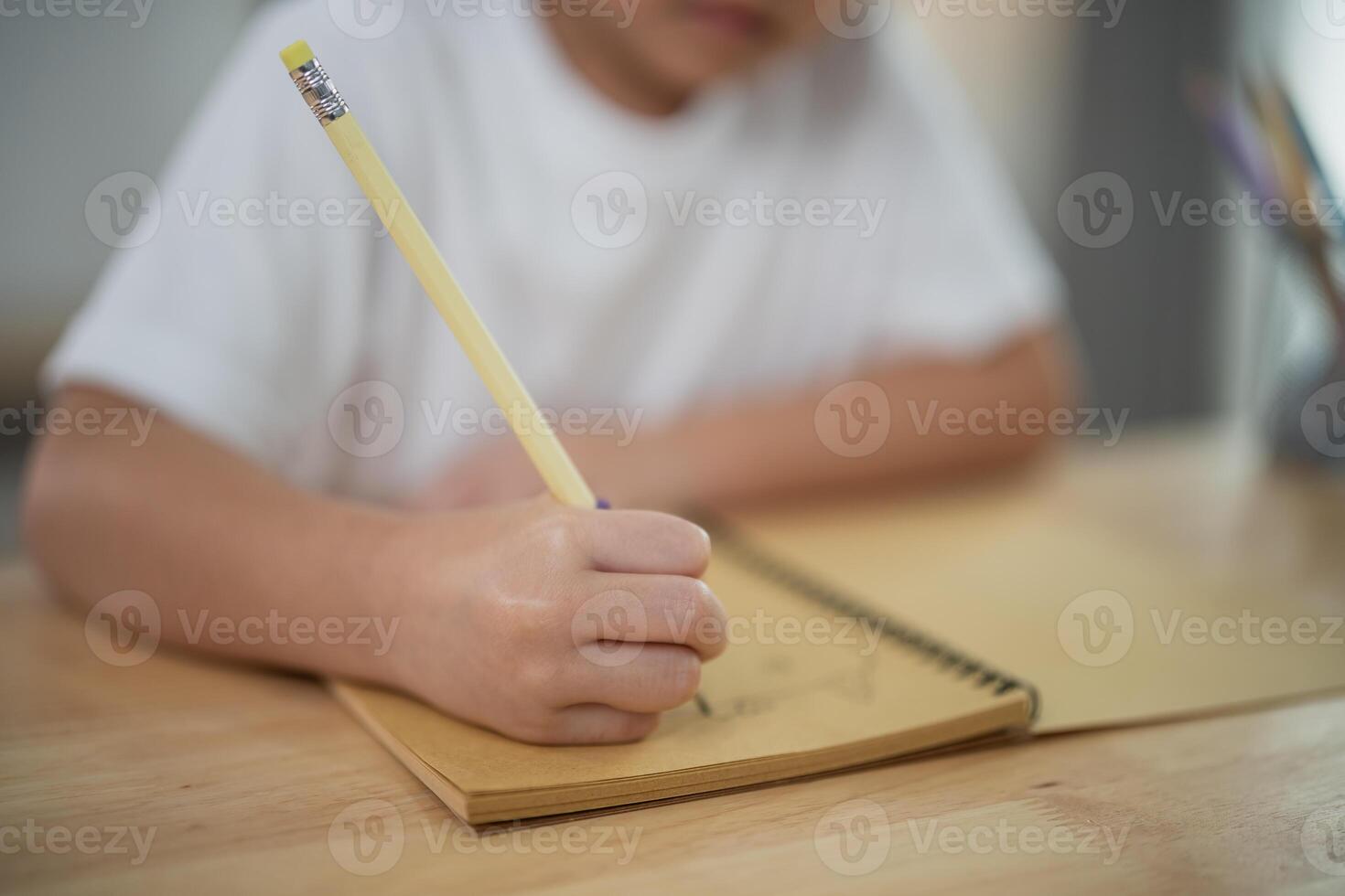 Child Drawing with Pencil on Notepad, Creative Expression in Art, Focused Young Learner, Developmental Activity for Children, Learning through Creativity photo