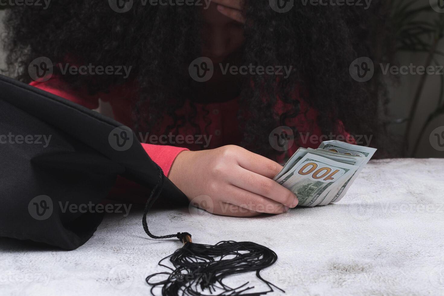 A young woman hand taking US dollar cash next to graduation cap or hat. photo