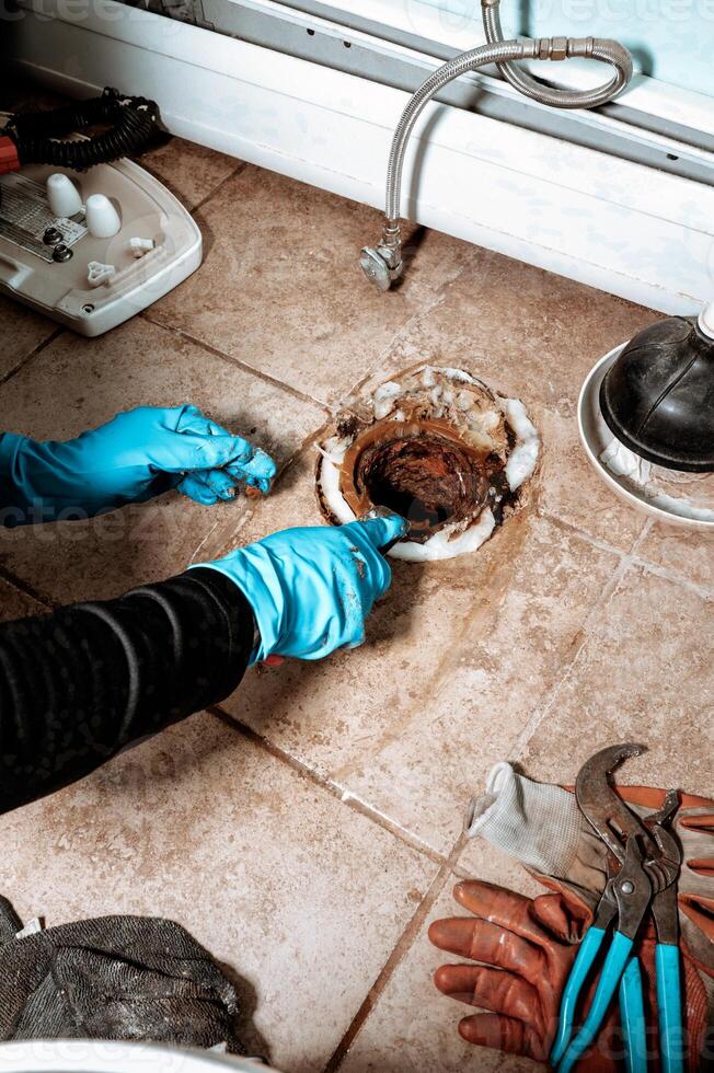 Close-up view of a Professional plumber replacing old wax ring seal before toilet installation. photo