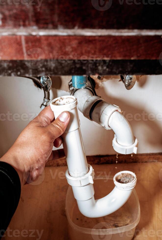 Close-up image of a person holding a clogged P-trap pipe photo