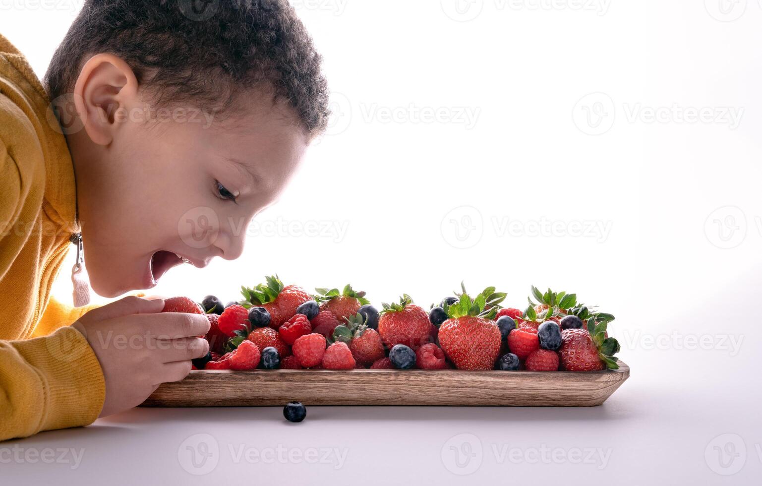 child taking fresh berries isolated on white background. photo