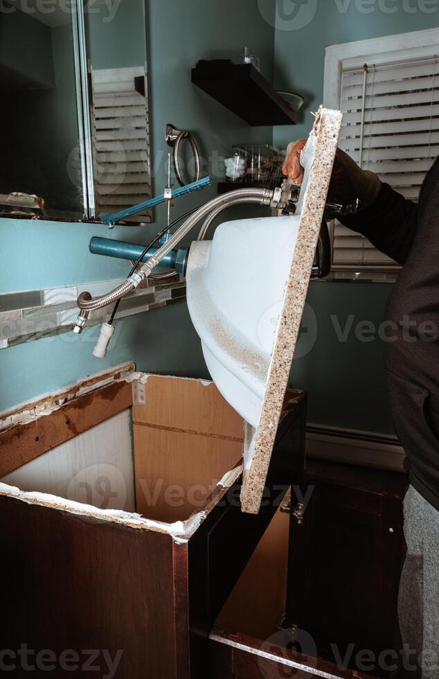 Man replacing an old sink in the bathroom plumbing repair, bathroom renovation, home improvement, handyman service, sink installation, DIY project, faucet replacement, bathroom maintenance. photo