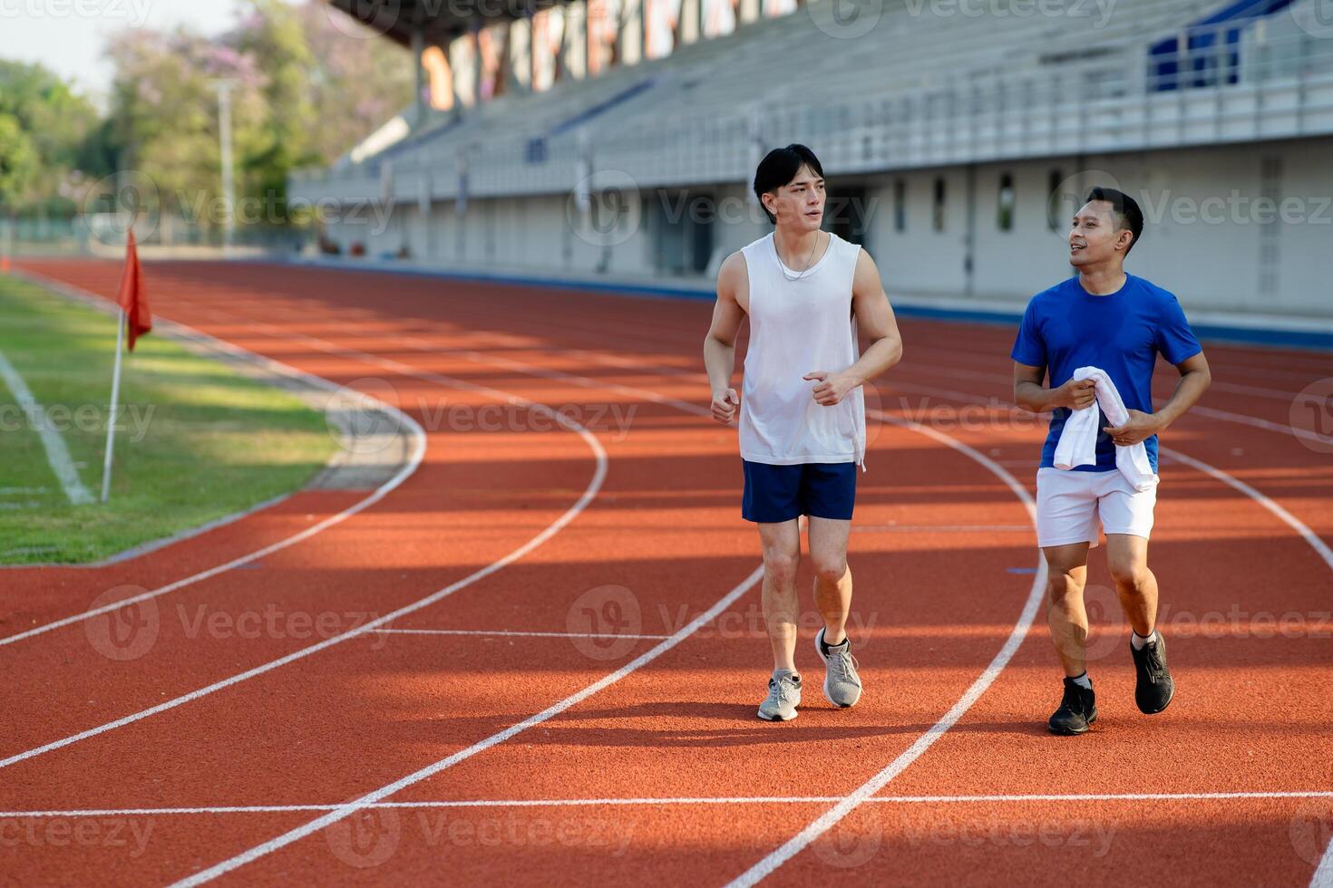 Two asian athlete men or male friends are running together on racetrack in the sports stadium. photo