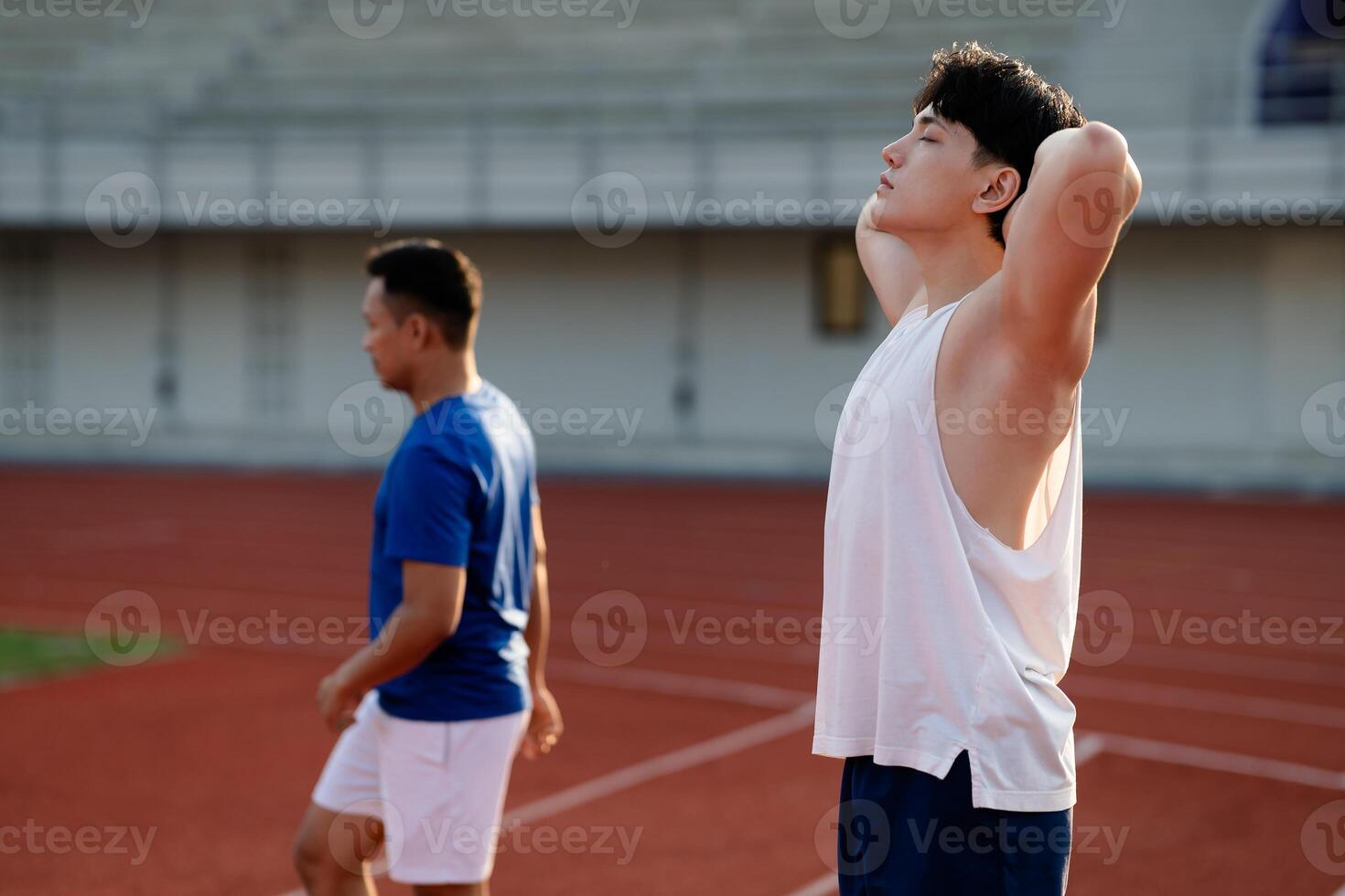 Two asian athlete men are standing leisurely on the racetrack in sports stadium. photo