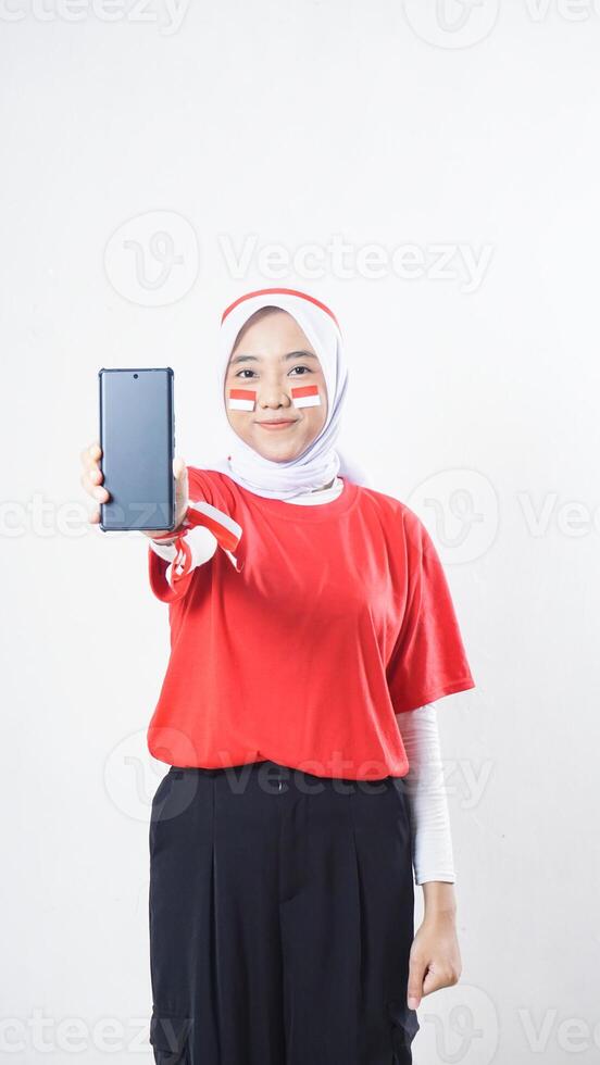 Indonesia independence day celebration with Asian girl wearing red and white Indonesia flag color attribute showing smartphone with blank screen isolated on white background photo