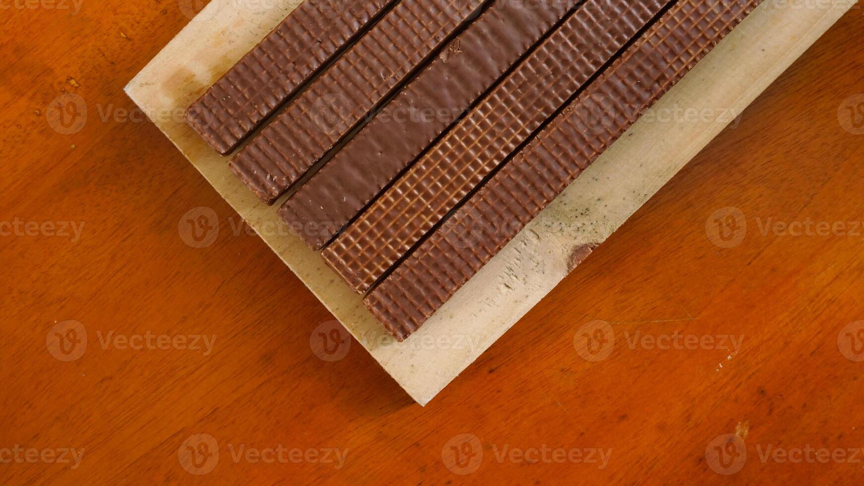 Top view of chocolate wafer sticks on a wooden board isolated on wooden textured background photo
