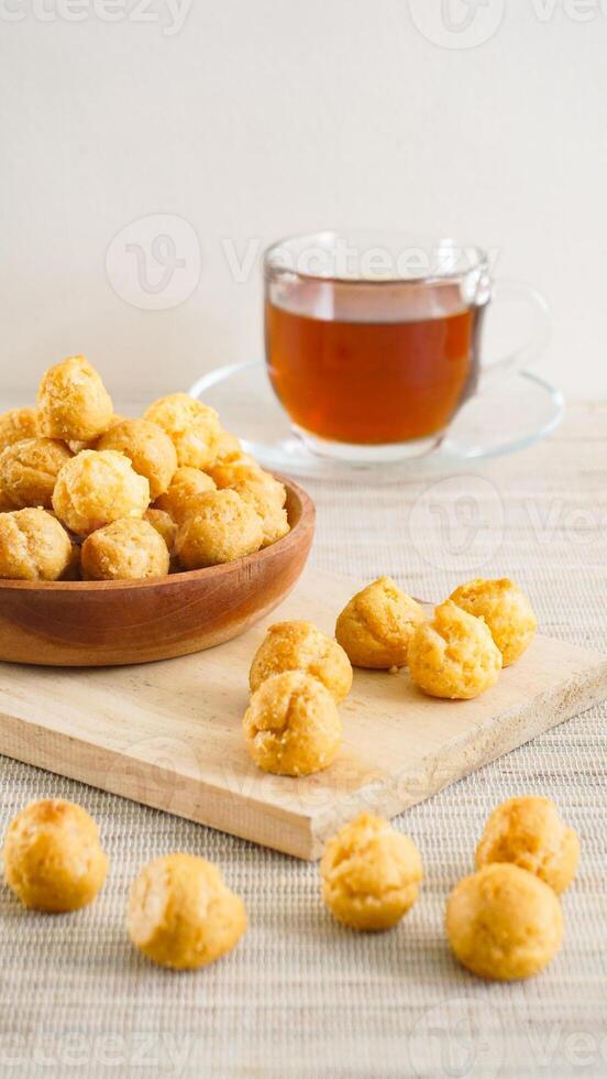Dried choux pastry filled with cheese cream on a plate with a cup of tea isolated on wooden textured background photo