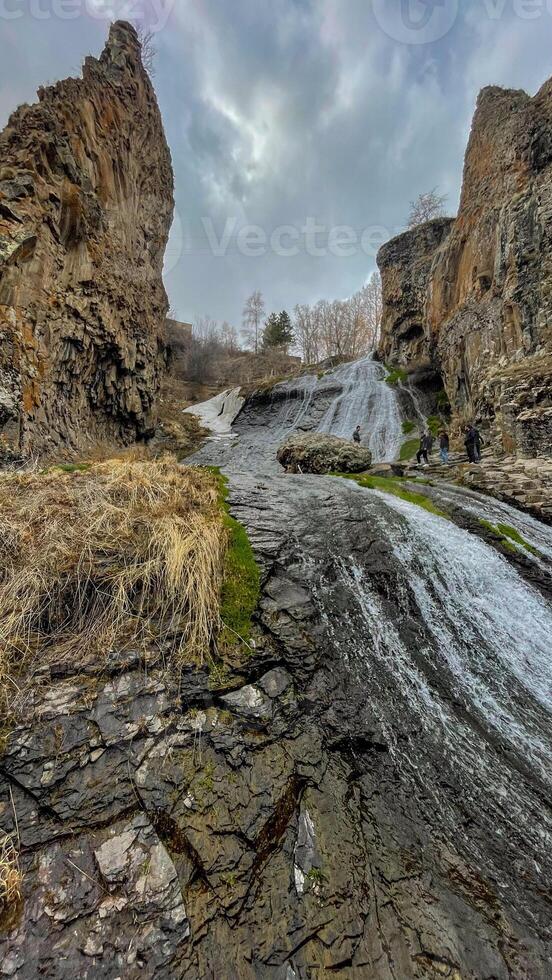 Majestic waterfall cascades through rugged cliffs, ancient stones whispering secrets, perfect for National Geology Day or Earth Heritage Celebration photo