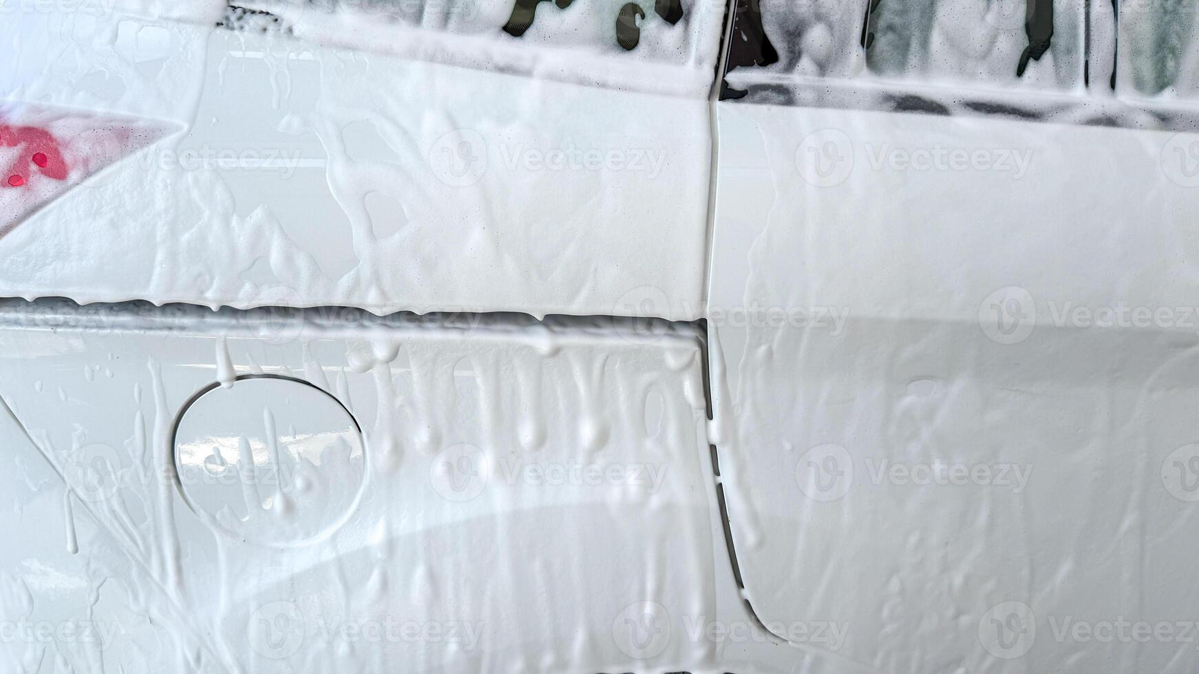 Suds cling to white car body, a frothy embrace reminiscent of Bubble Bath Day, cleansing ritual reborn in urban zen photo