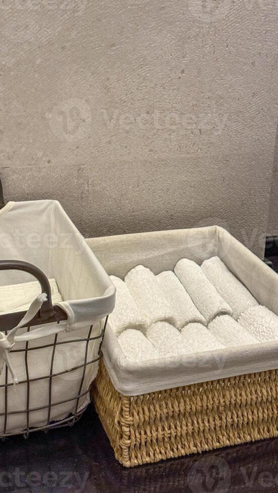 Neatly rolled white towels nestle in wicker baskets, evoking Hygge coziness and spring cleaning rituals, perfect spa elegance photo