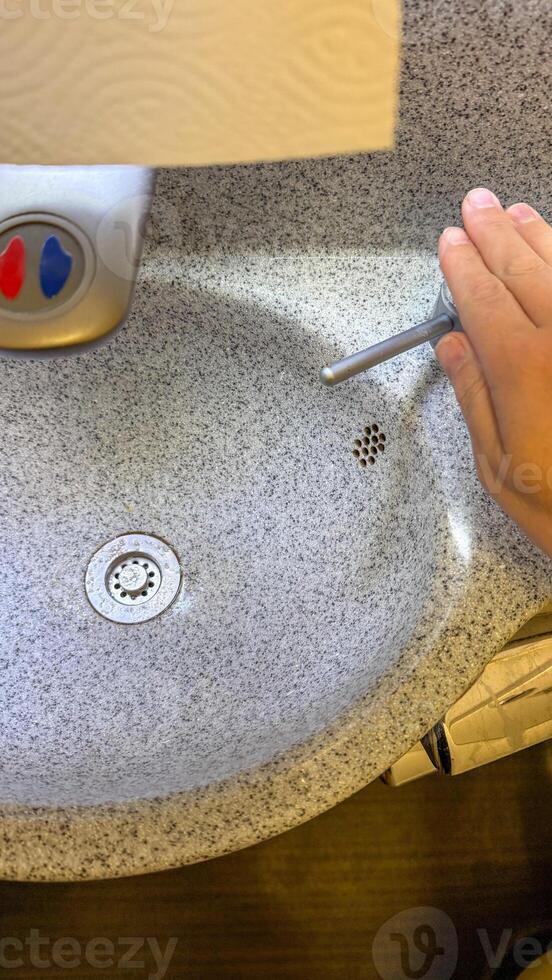 A hand poised over a minimalist sink evokes Hygge inspired tidying rituals and World Plumbing Day celebrations photo