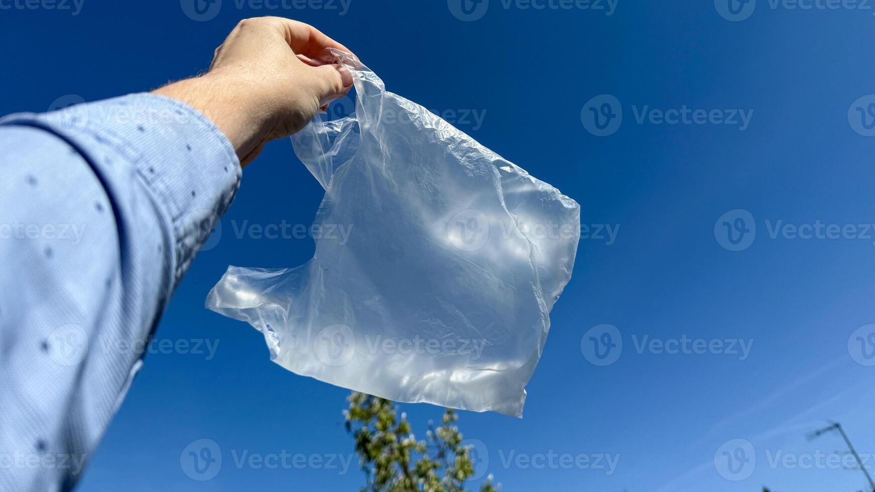 Elevated against a cerulean sky, a translucent plastic bag dances whimsically, reminiscent of International Plastic Bag Free Day photo