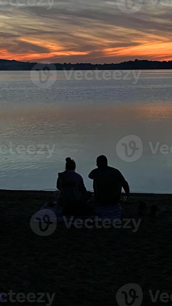 Couple man and woman on the shore watching the sunset over the water. Poland photo