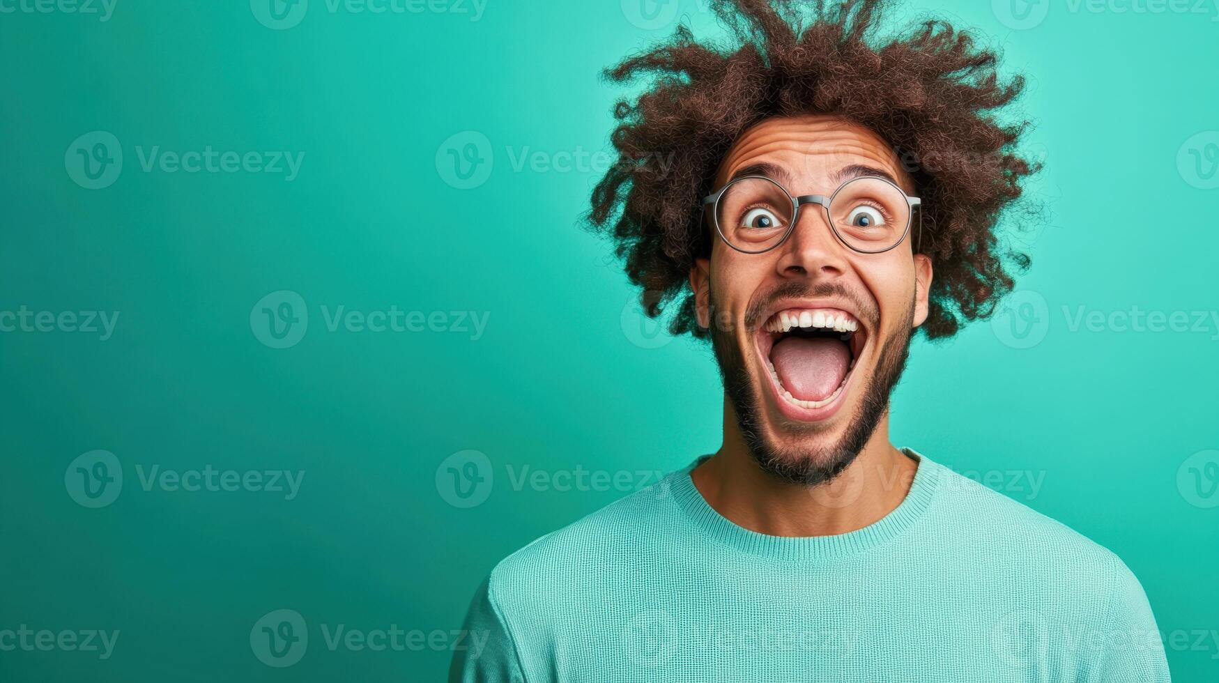 Young man with curly hair showing excitement against a vibrant green background during a playful moment, showcasing joy and happiness photo