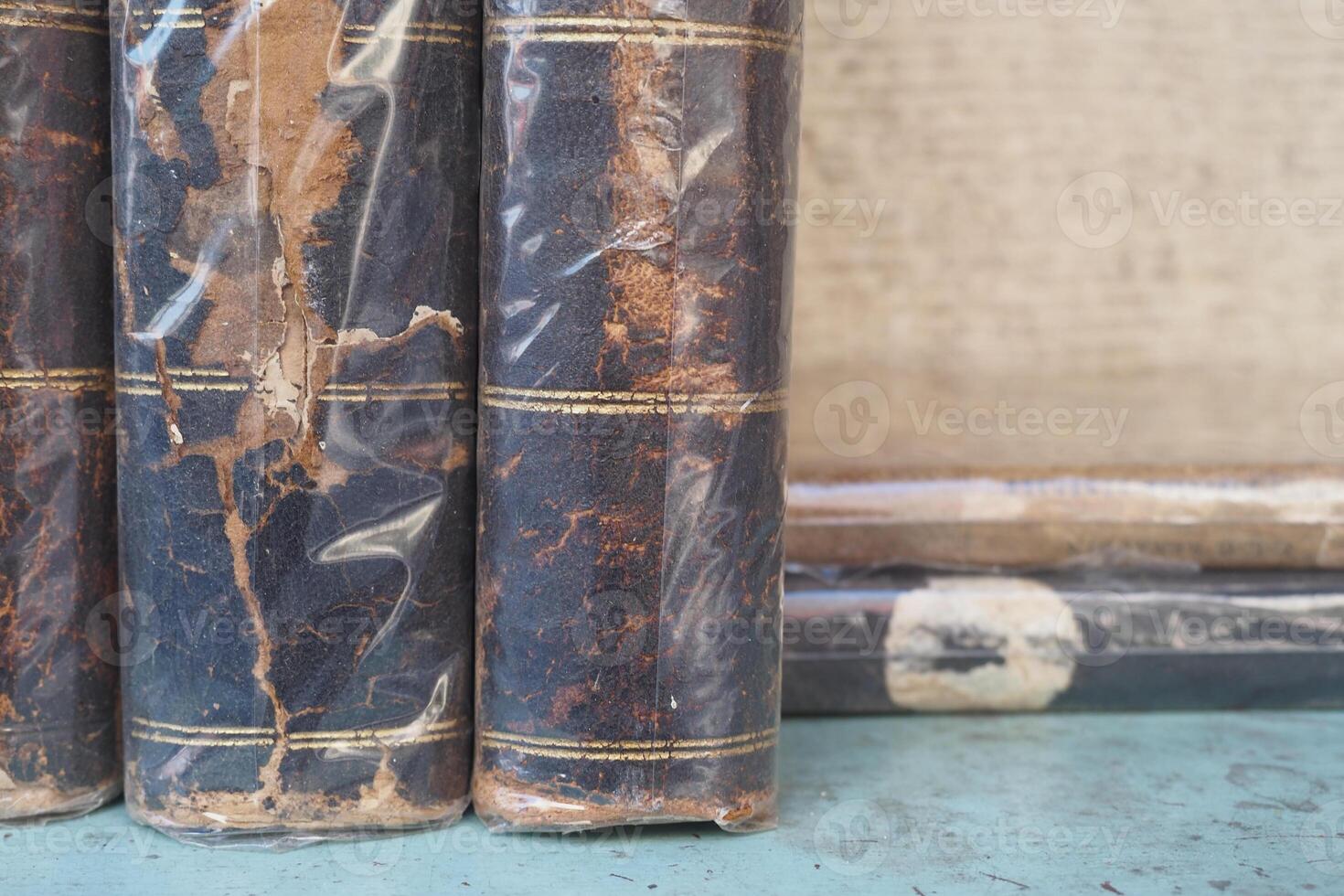 Old leather-bound books stacked on a wooden table photo